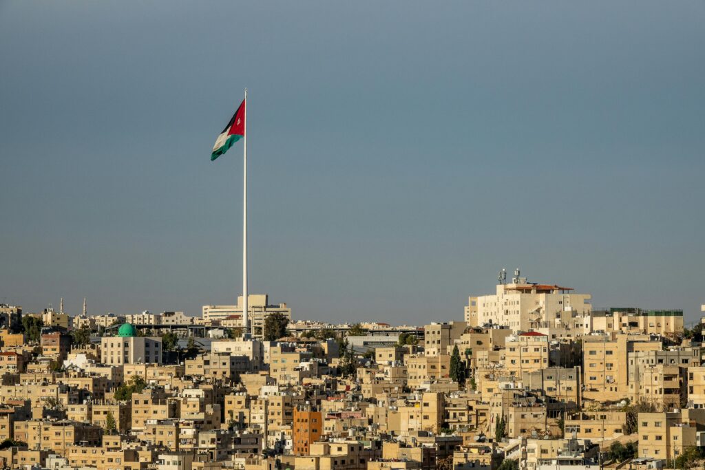 View of Amman's cityscape featuring the towering Jordanian flag under a clear sky.