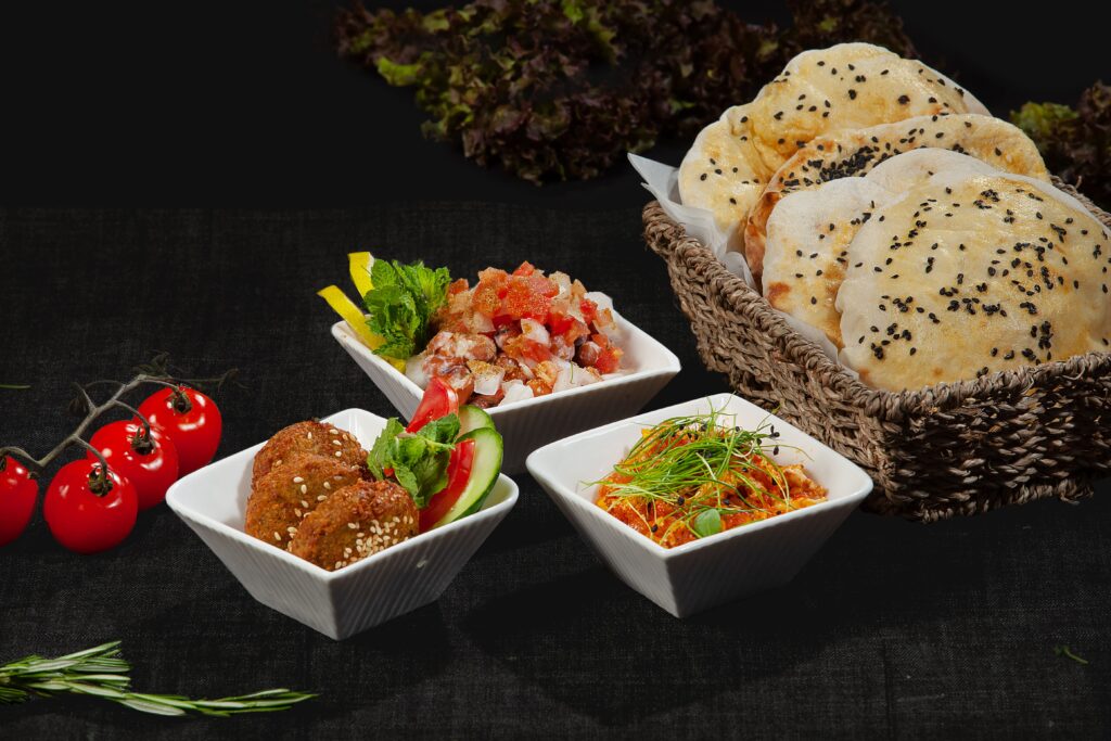 A delicious spread of Middle Eastern dishes featuring sesame bread, fresh dips, and cherry tomatoes.