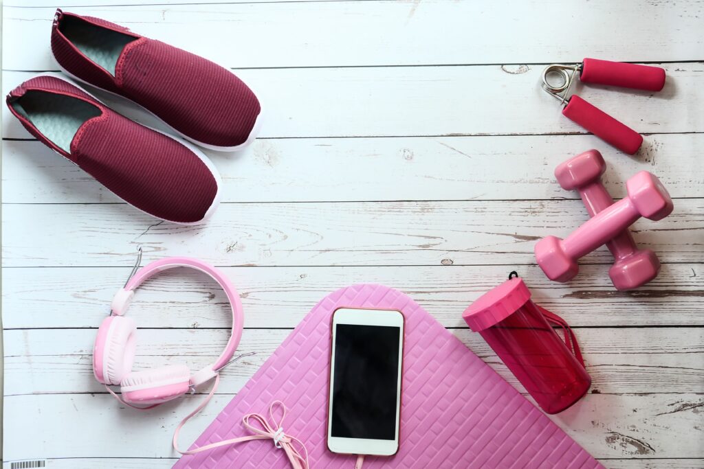 A flat lay of pink fitness items on white wood, ideal for lifestyle imagery.