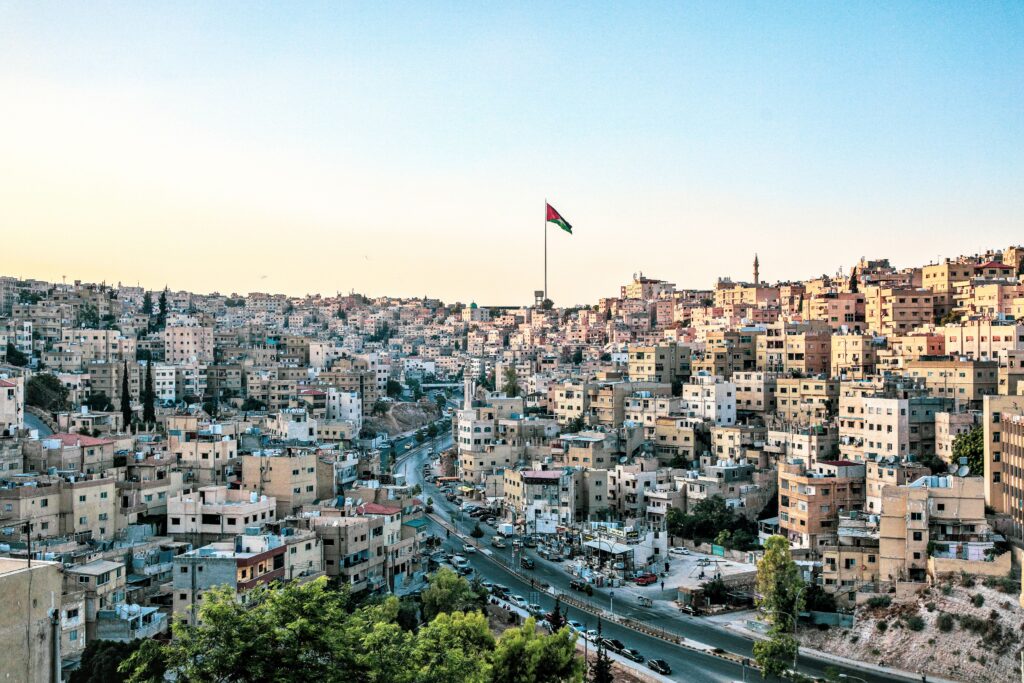 High angle view of Amman, Jordan with its distinct skyline and prominent flag under a clear sky.
