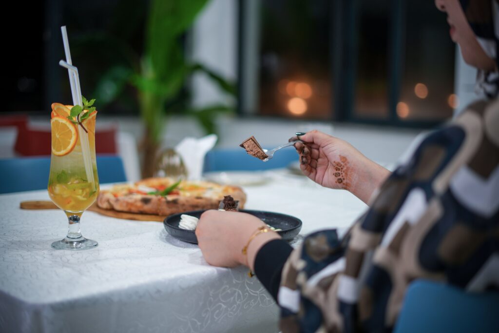 Close-up of a person dining with pizza and cocktail indoors, capturing a relaxed and elegant atmosphere.