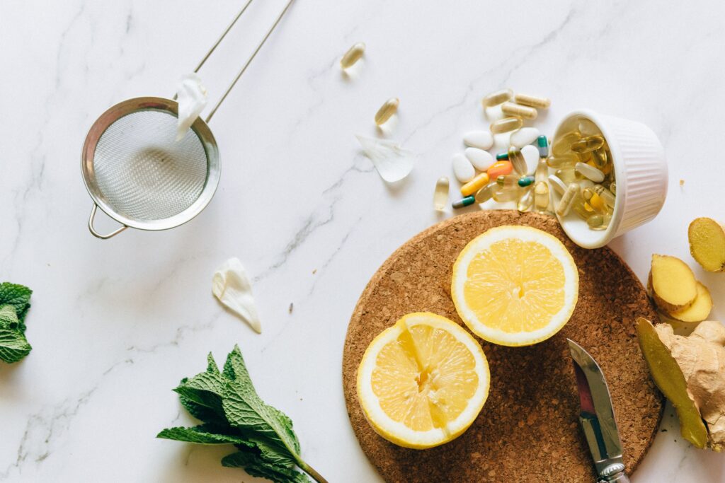 Flat lay of lemon, ginger, and supplements on a marble surface, illustrating natural remedies.