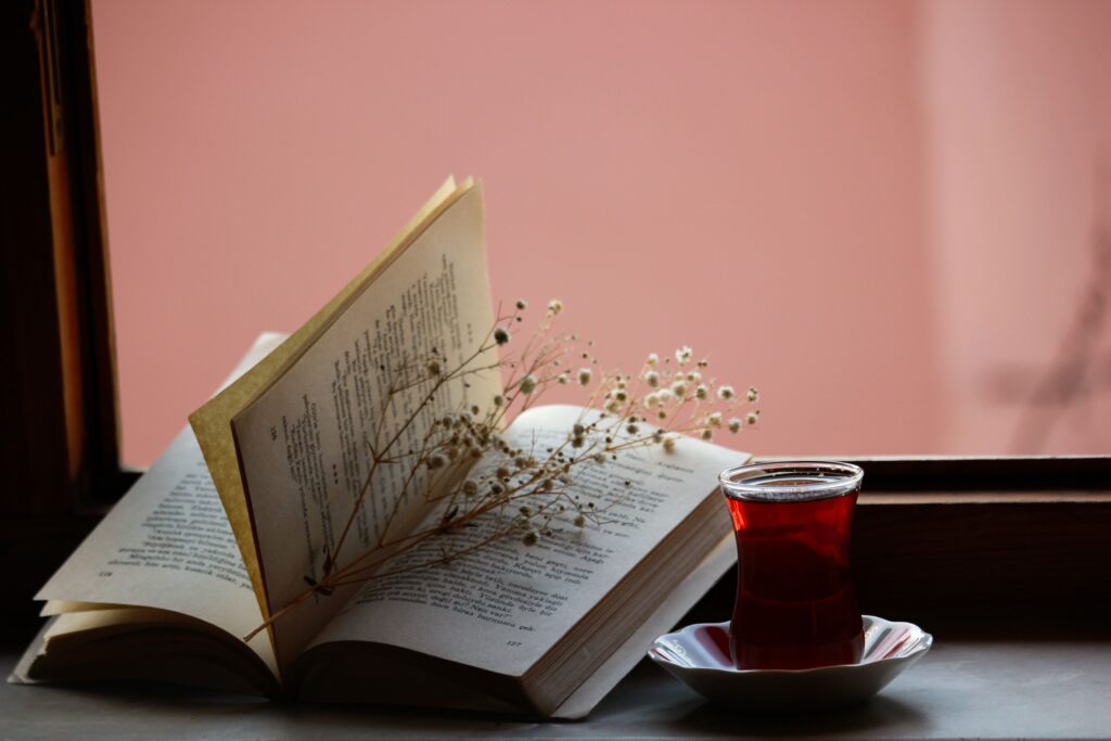 A cozy window nook with a book, tea, and wildflowers creates a peaceful reading atmosphere.